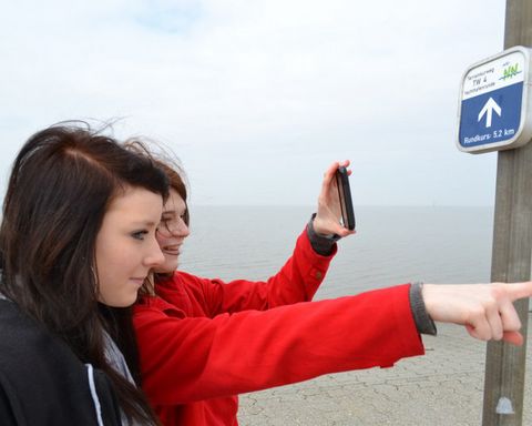 Zwei Frauen am Wattenmeer vor einem Schild der Terrainkurwege.